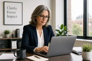Active woman in her 50s working thoughtfully at a laptop in a modern, well-lit office, reflecting focus and professionalism.