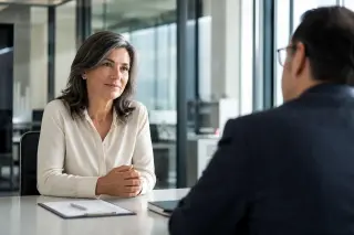 Confident woman in her early 50s engaged in a professional job interview in a modern, bright office setting.